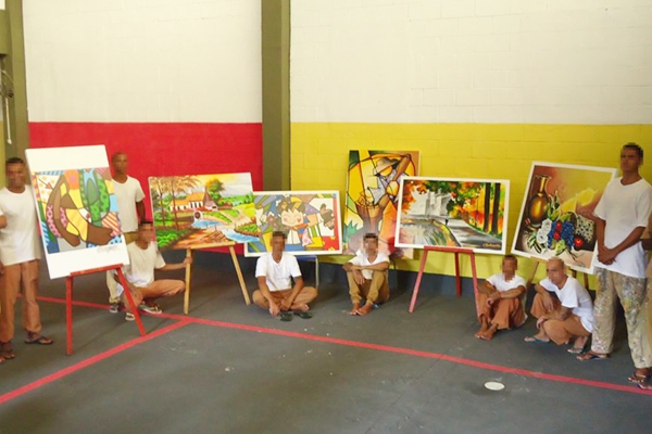 Reeducando ao lado das artes criadas durante o projeto – Foto: divulgação